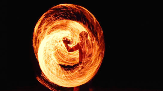 A person swirling a burning rope forming a litteral firewall in front of them.